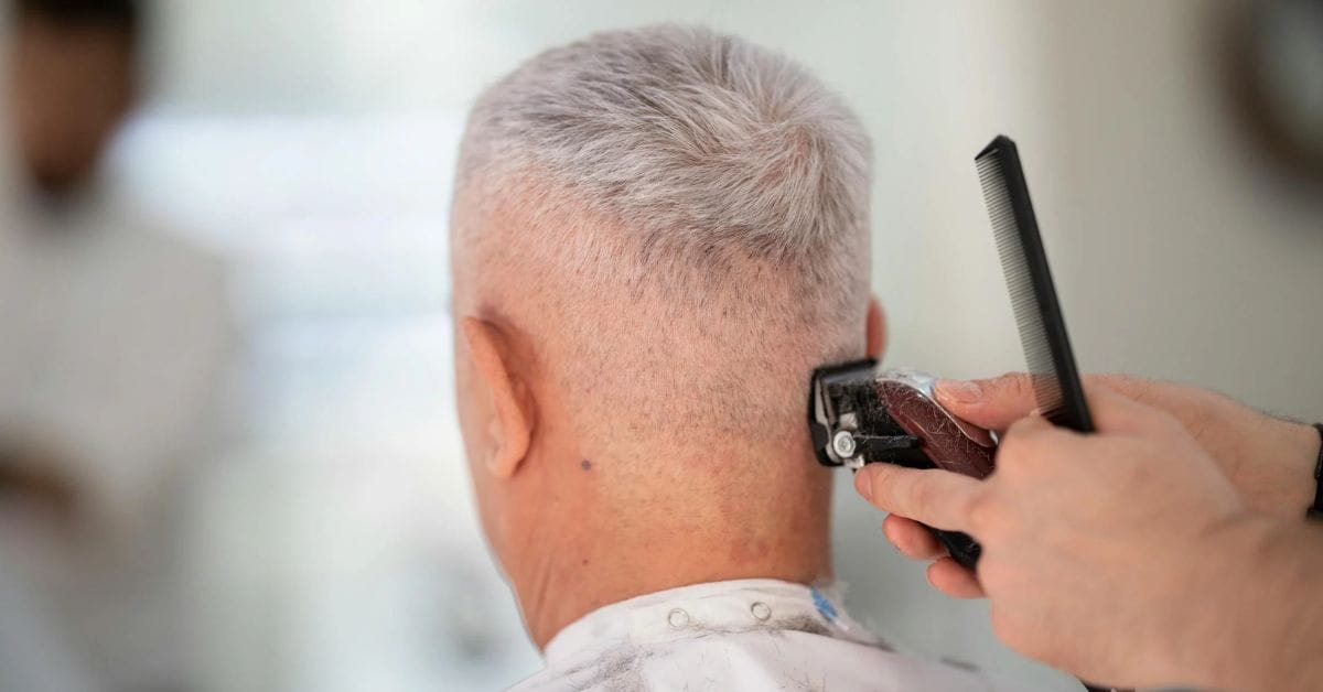 A man receiving a classic Old Money haircut from a skilled barber in a stylish barbershop setting