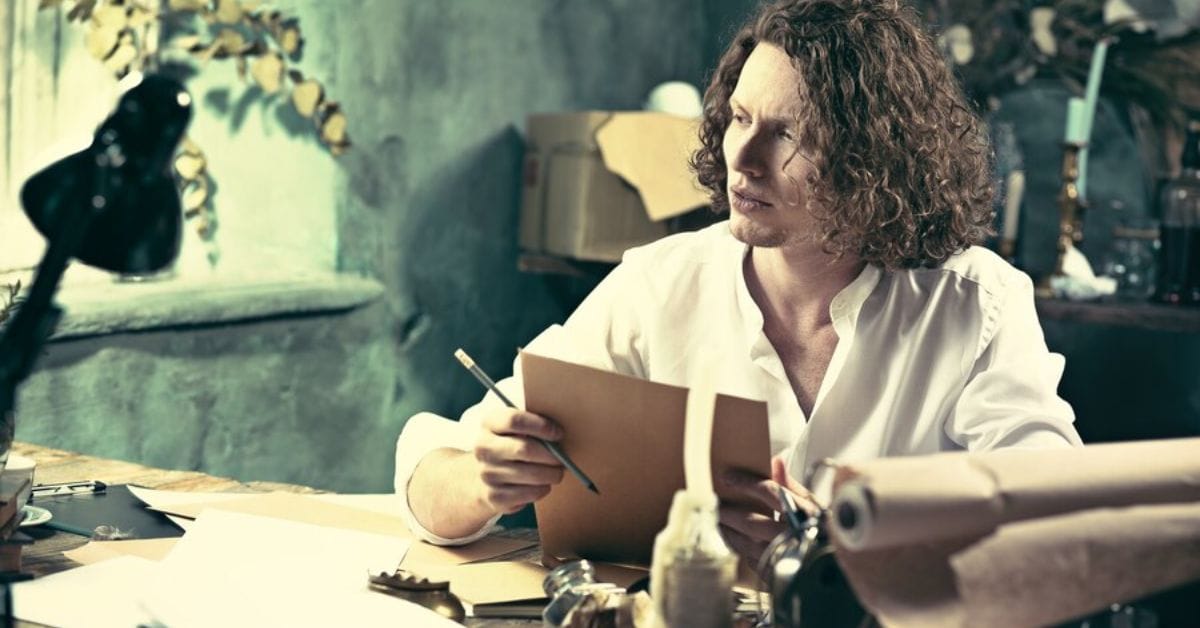 A man with curly hair sits at a desk, surrounded by papers, embodying the essence of Old Money Style.