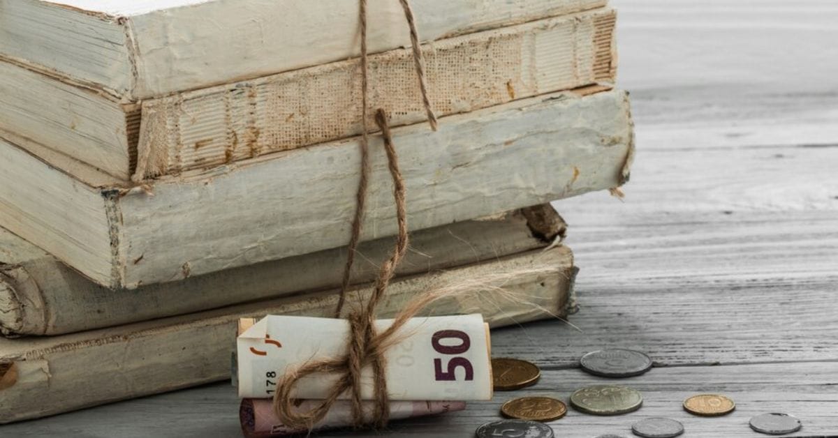 A stack of vintage books with cash tied around them, symbolizing budget-friendly old money style.
