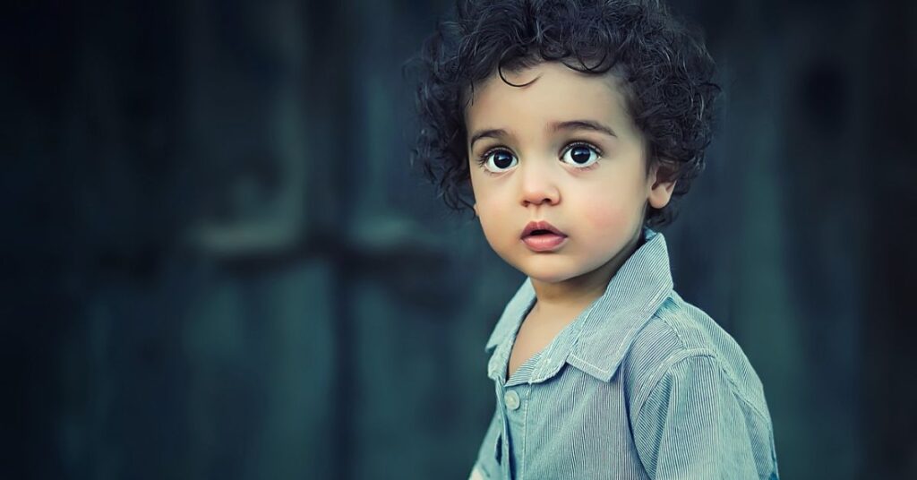 A young boy with curly hair gazes upward, embodying a classic charm reminiscent of old money elegance.