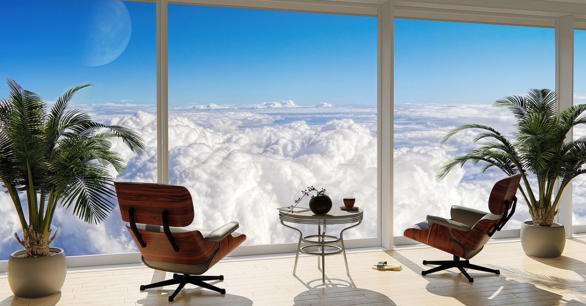 Cozy living room with two stylish chairs and a table, offering a serene view of fluffy clouds outside.